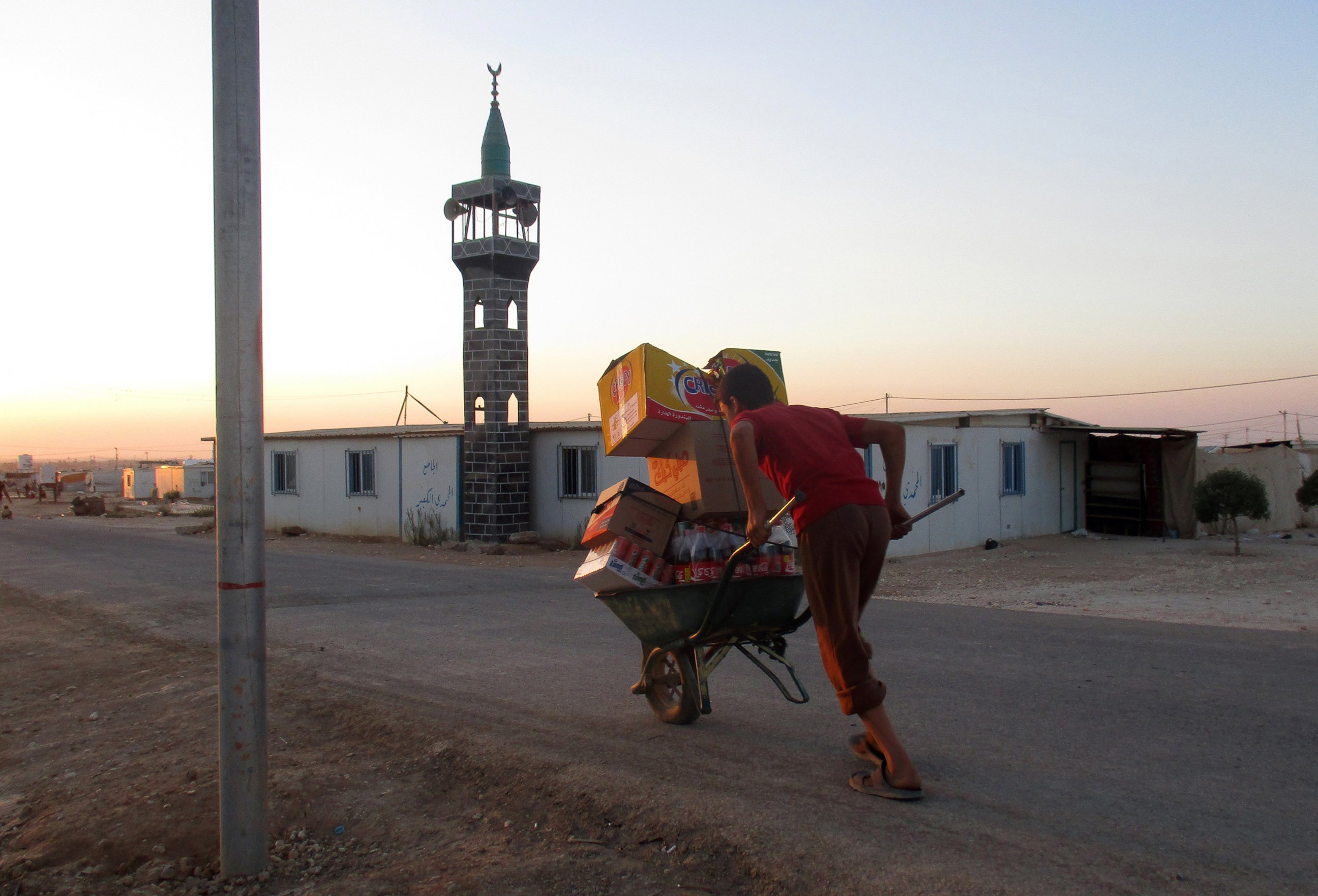 PHOTO: A boy about my age transports items on a wheelbarrow past the mosque.