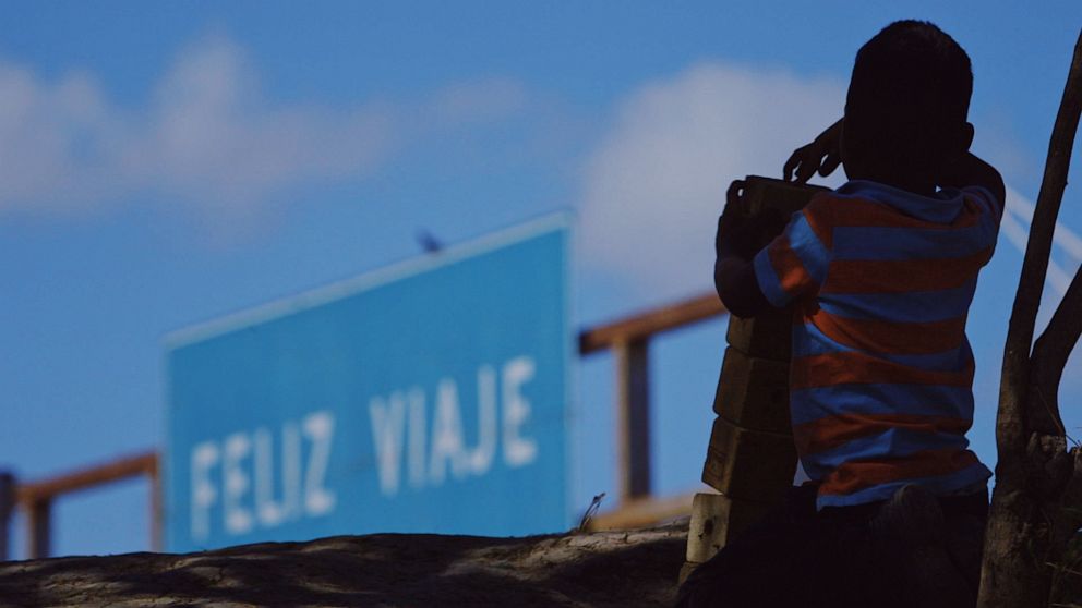 PHOTO: A child living in a makeshift camp in Mexico looks out toward a sign that says, "Have a good trip."  