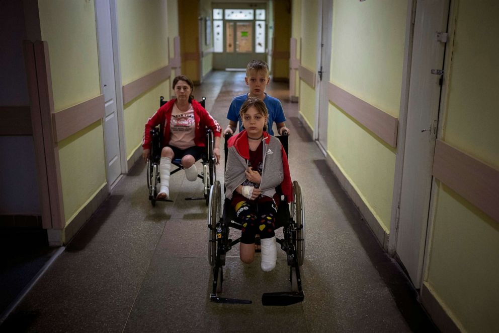 PHOTO: Followed by their mother Natasha, Yarik Stepanenko pushes his twin sister Yana's wheelchair along a hospital corridor in Lviv, Ukraine, May 12, 2022. A missile struck the train station where they were planning to catch an evacuation train.