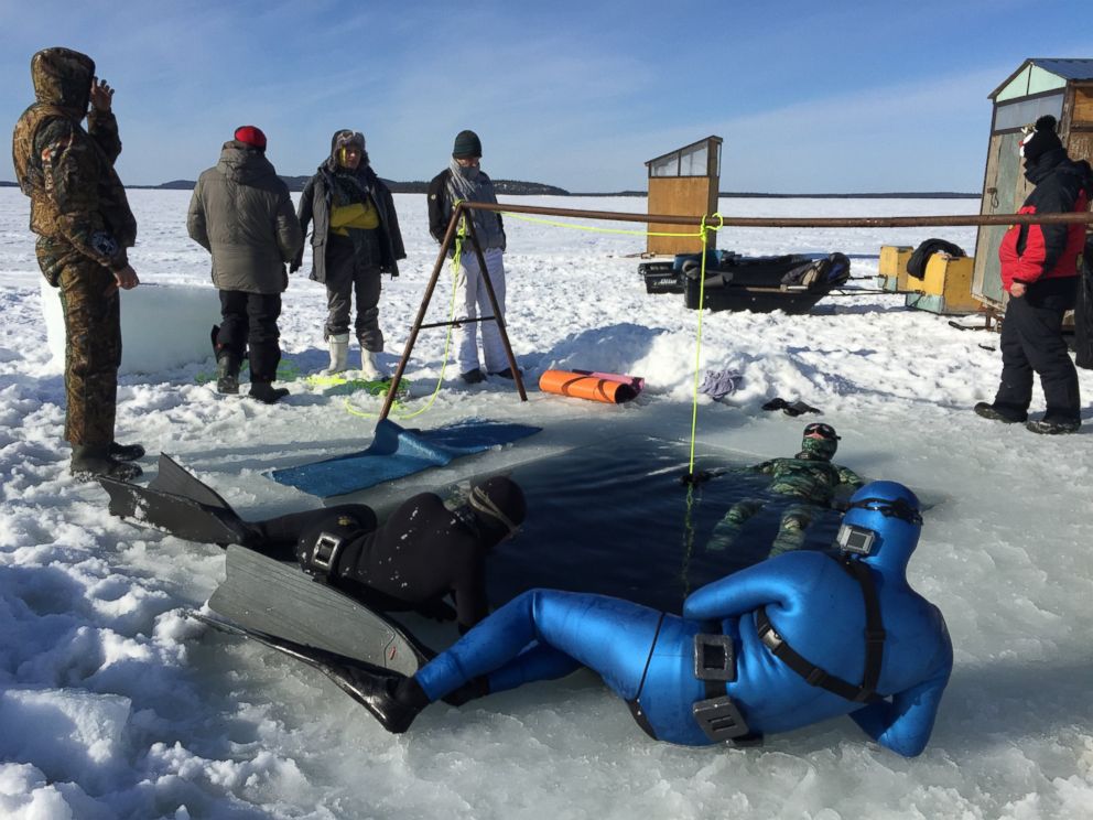 PHOTO: A group of divers do breathing exercises before a dive, one lying in the water. Divers have to acclimatize to the freezing temperatures and calm themselves before going under.