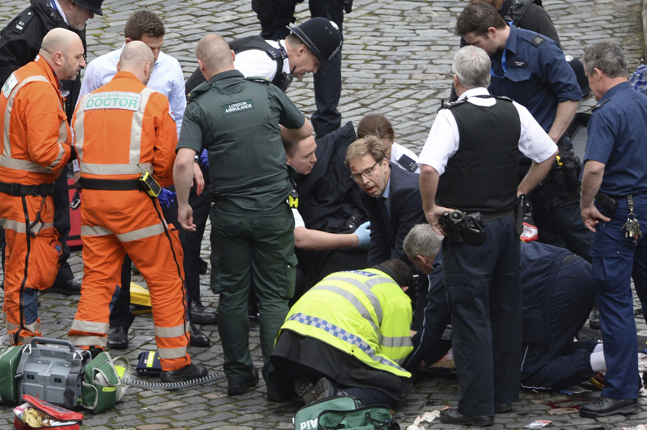 PHOTO: Conservative Member of Parliament Tobias Ellwood, center, helps emergency services attend to an injured person outside the Houses of Parliament, London, on March 22, 2017. 