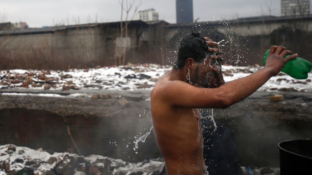 A migrant washes himself outside a crumbling warehouse that has served as a makeshift shelter in Belgrade, Serbia, Jan. 14, 2017. Migrants have been exposed to freezing temperatures and snow as extreme winter weather gripped Serbia and other parts of Europe last week. 