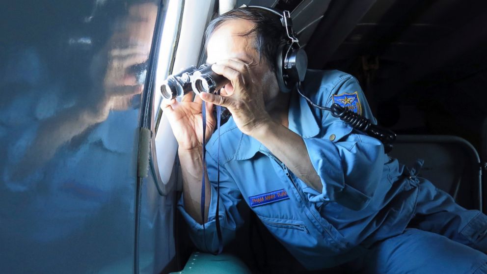 Vietnamese Air Force Col. Pham Minh Tuan uses binoculars on board a flying aircraft during a mission to search for the missing Malaysia Airlines flight MH370 in the Gulf of Thailand over the location where Chinese satellite images showed possible debris from the missing Malaysian jetliner, Thursday, March 13, 2014.
