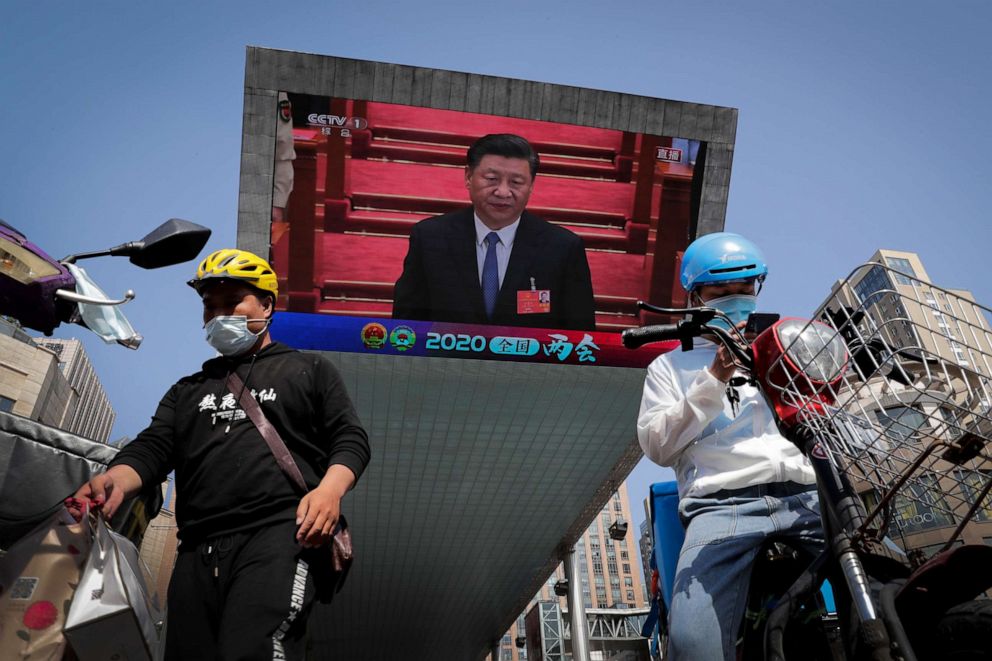 PHOTO: Food delivery workers wearing face masks to protect against the spread of the new coronavirus prepare to delivery foods near a TV screen showing Chinese President Xi Jinping attending the closing ceremony of the National People's Congress.