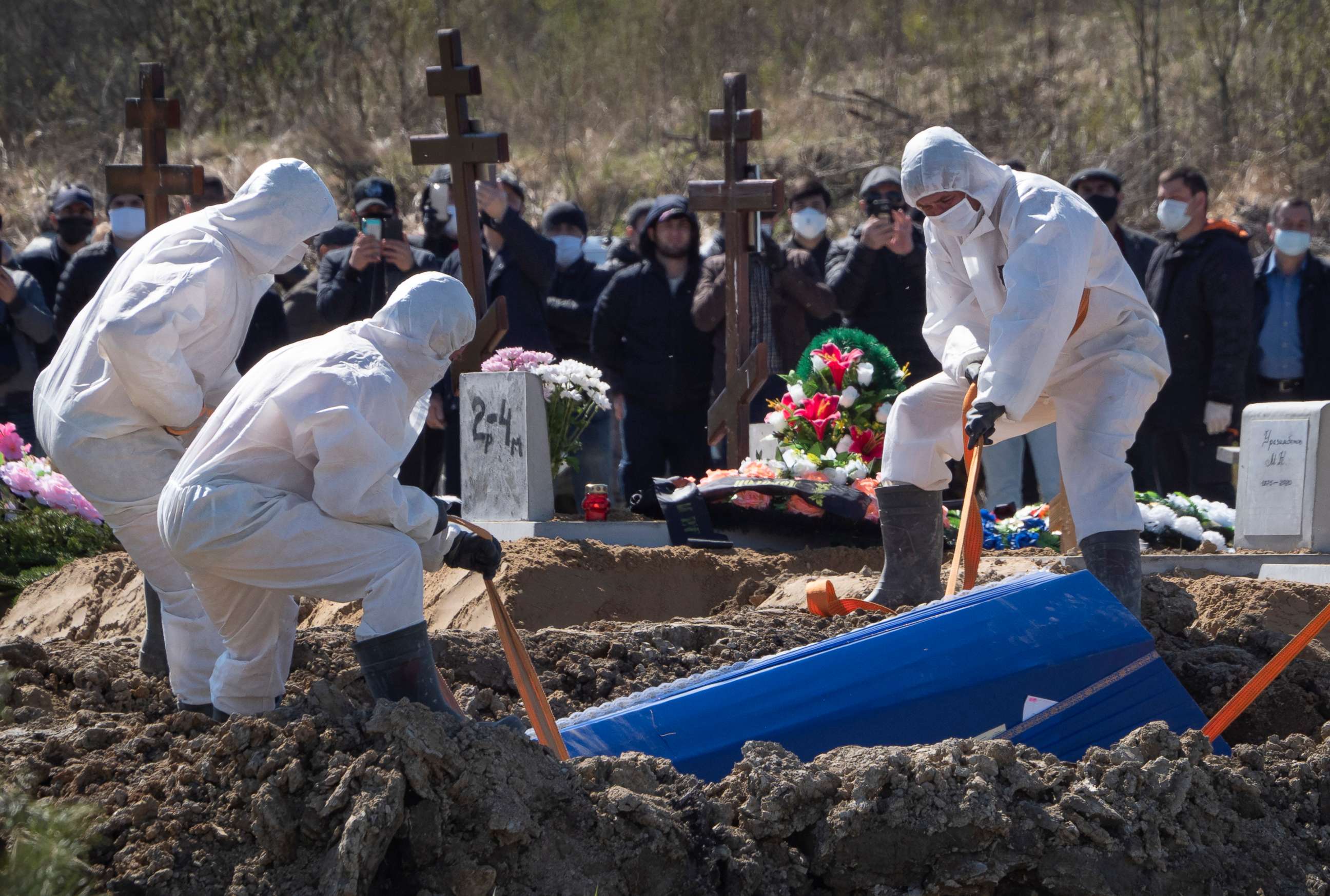 PHOTO: Grave diggers wearing protective suits bury a COVID-19 victim as relatives and friends stand at a safe distance, in the special purpose for coronavirus victims section of a cemetery in Kolpino, outside St.Petersburg, Russia, Sunday, May 10, 2020.