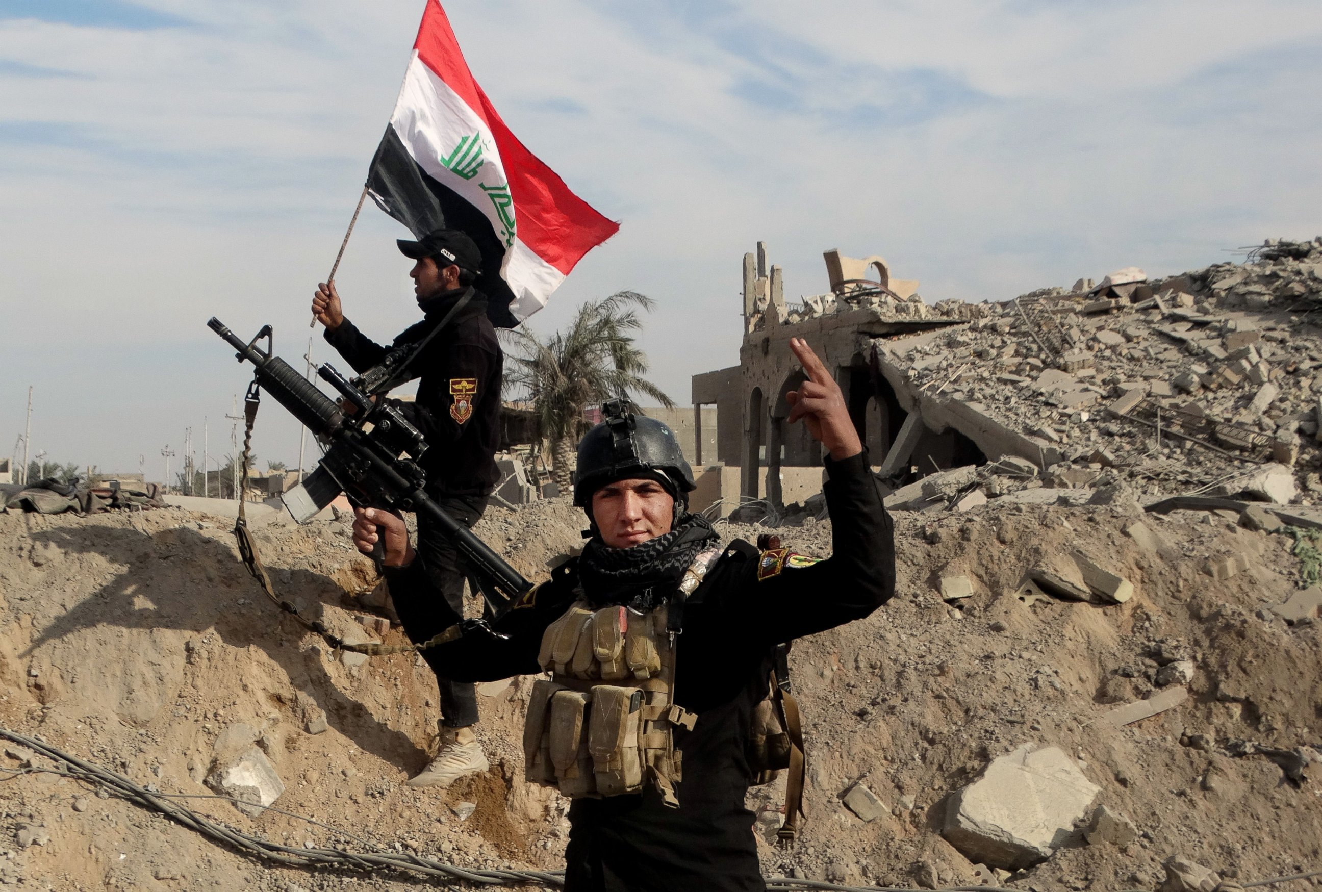 Iraqi security forces raise an Iraqi flag near the provincial council building in central Ramadi.
