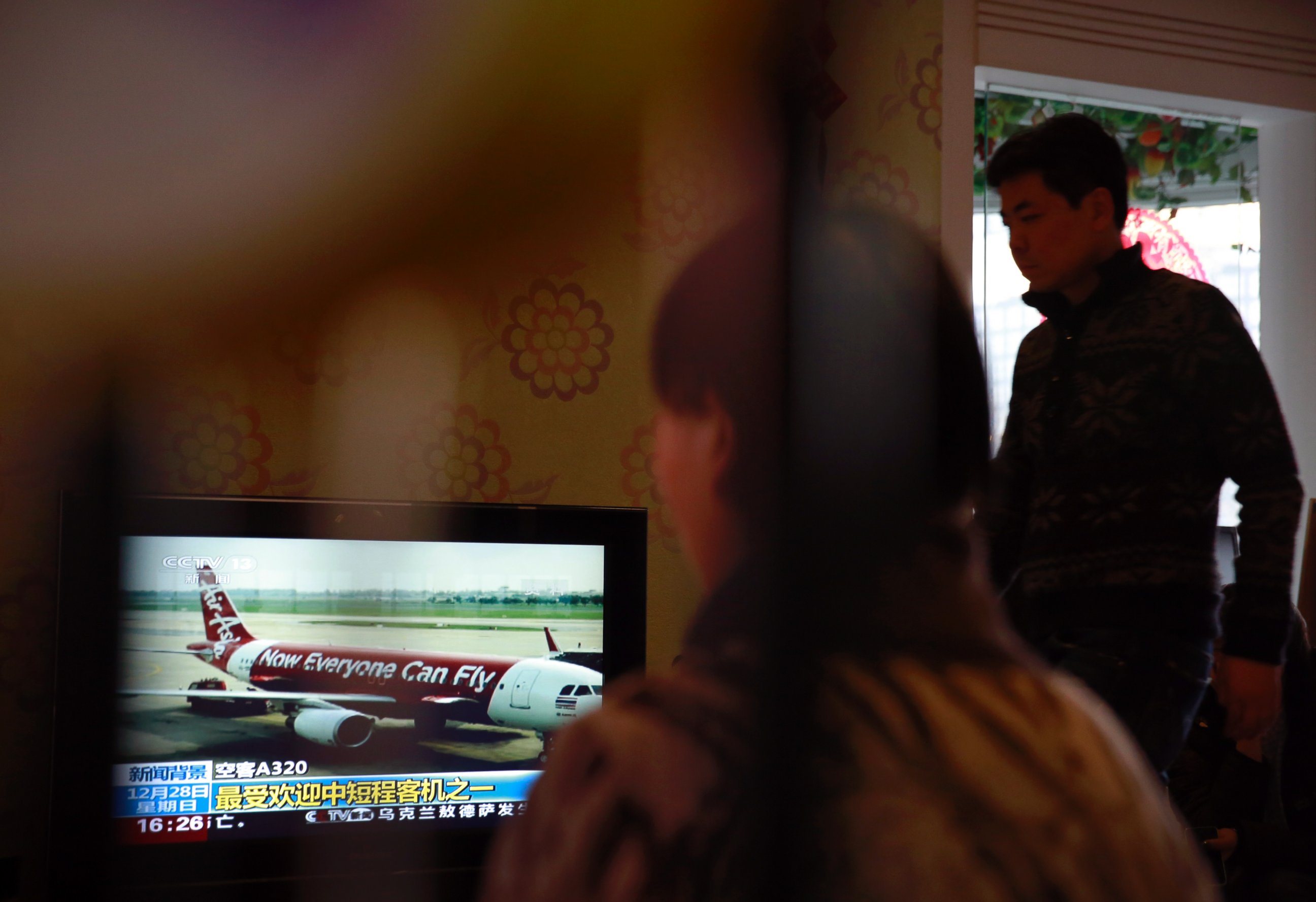 Relatives of passengers onboard the Malaysia Airlines Flight 370 that went missing on March 8, 2014, watch TV news about missing AirAsia flight QZ8501, during their year-end gathering at a house in Beijing, China Sunday, Dec. 28, 2014. 