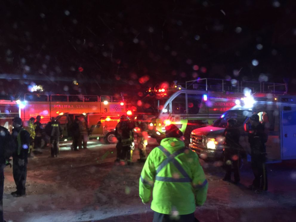 Fire trucks and an airport shuttle are on the scene at the Halifax International Airport early Sunday March 29, 2015 after an Air Canada flight from Toronto made an abrupt landing and left the runway in bad weather. 