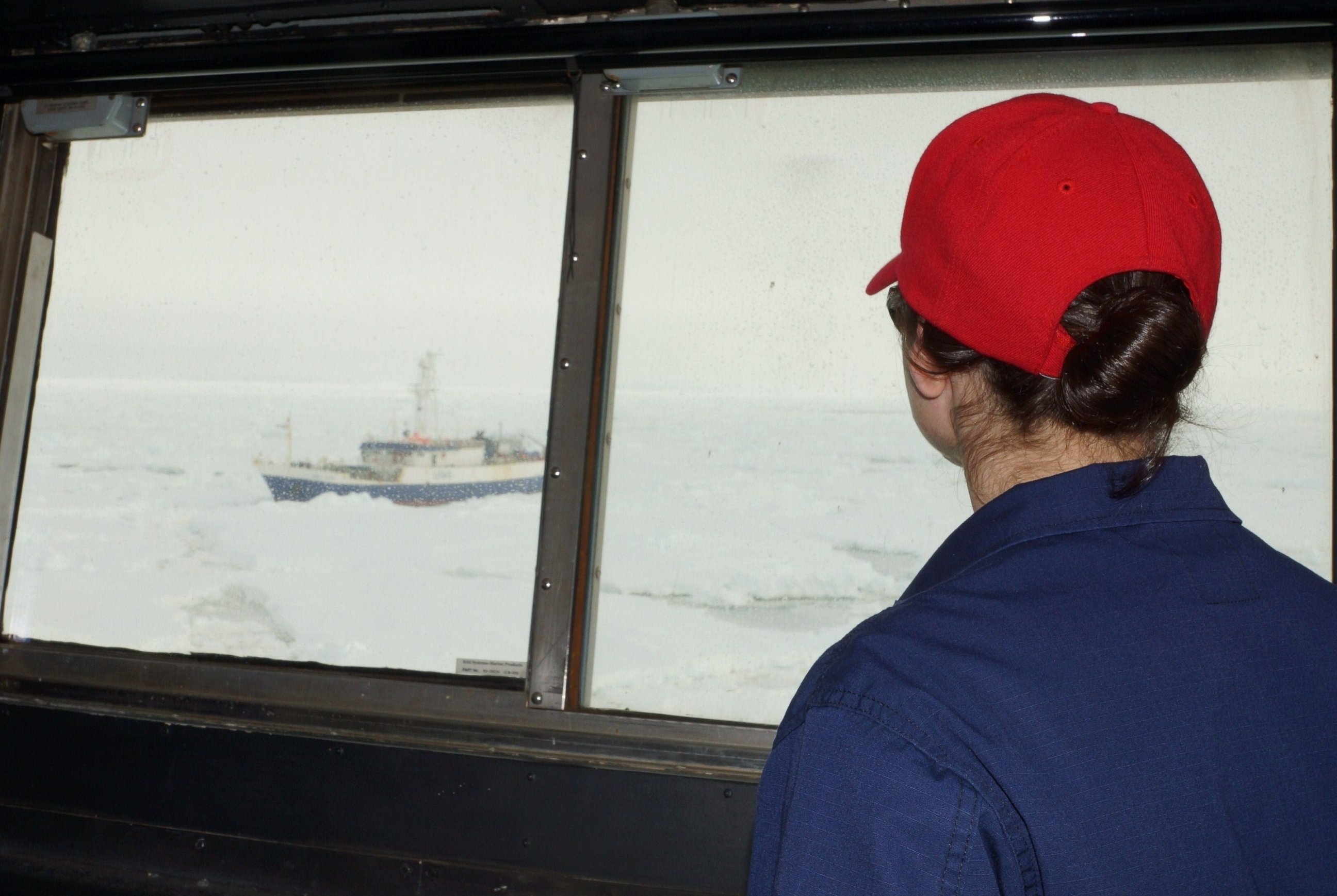 PHOTO: A crew member of the Coast Guard Cutter Polar Star watches out of a window aboard the cutter as the Antarctic Chieftain comes into view and the cutter begins breaking up the ice around the fishing vessel Feb. 13, 2015.