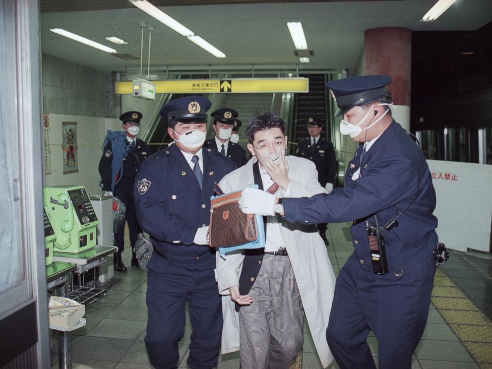 PHOTO:In this file photo, a subway passenger with his mouth covered up by a handkerchief is escorted by masked policemen from Tokyos Akasaka Station as the station was filled by toxic fumes, March 20, 1995.