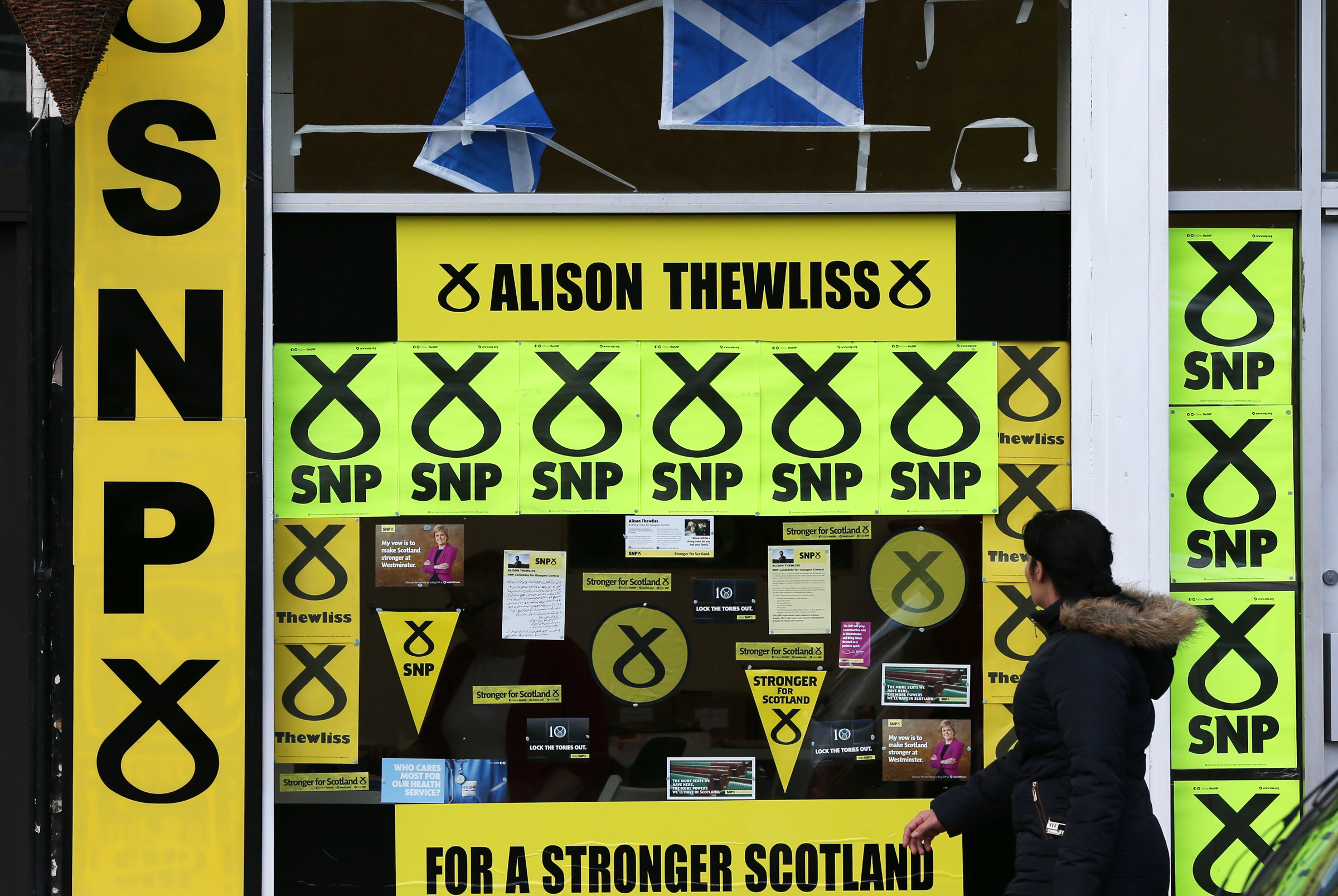 PHOTO: A member of the public walks past a window display of Scottish National Party branding is displayed in Glasgow, Scotland, May 7, 2015.