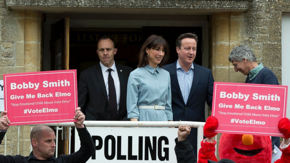 Britain's Prime Minister and Conservative Party leader David Cameron and his wife Samantha leave a voting station in Spelsbury, England, as protesters demonstrate outside after they voted in the general election, May 7, 2015.