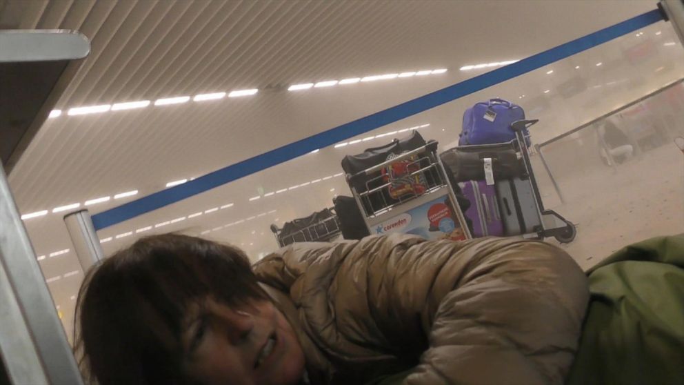 A traveler lies on the ground in a smoke filled terminal in a smoke filled terminal at Brussels Airport, in Brussels after explosions, March 22, 2016.