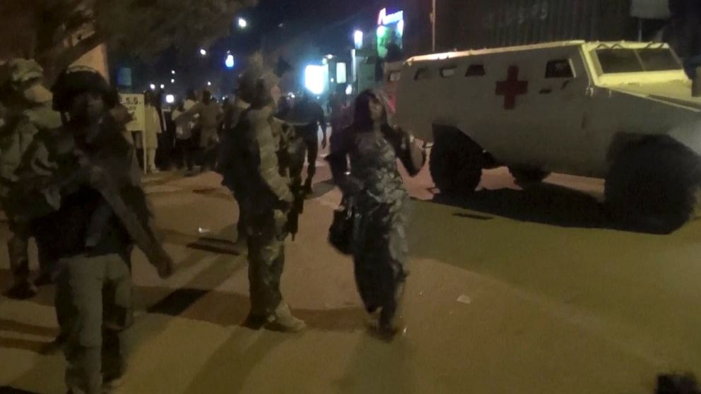 PHOTO: In this image taken from video from AP Television, a freed woman, center, walks past French special forces near the Splendid Hotel, early Saturday, Jan. 16, 2016, in Ouagadougou, Burkina Faso.