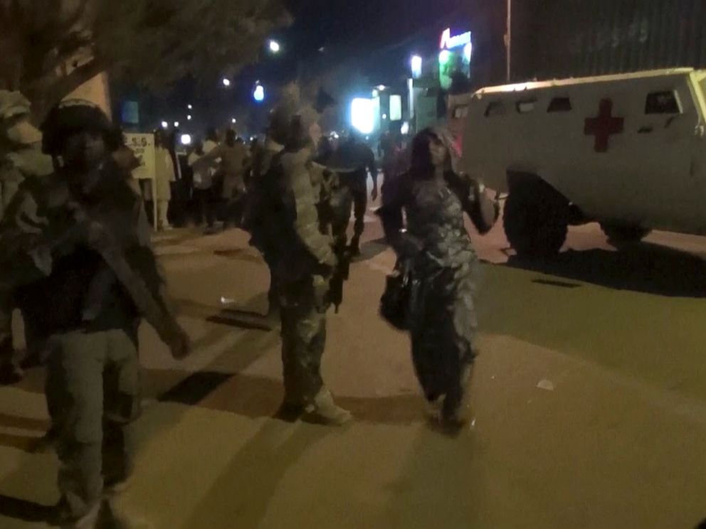 PHOTO: In this image taken from video from AP Television, a freed woman, center, walks past French special forces near the Splendid Hotel, early Saturday, Jan. 16, 2016, in Ouagadougou, Burkina Faso.