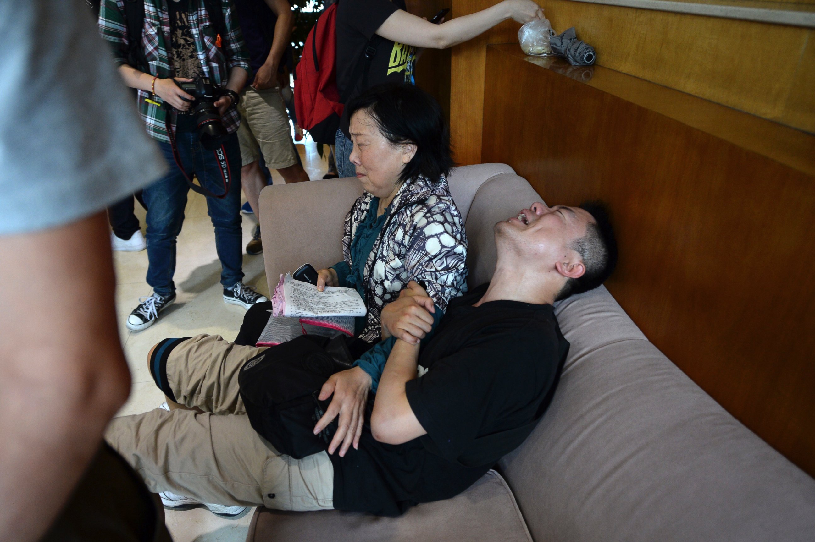 A man grieves for his missing parents next to his aunt outside a travel agency which was involved in organizing a Yangtze River cruise, in Shanghai, China, June 2, 2015. A small cruise ship sank overnight during a storm, state media said.