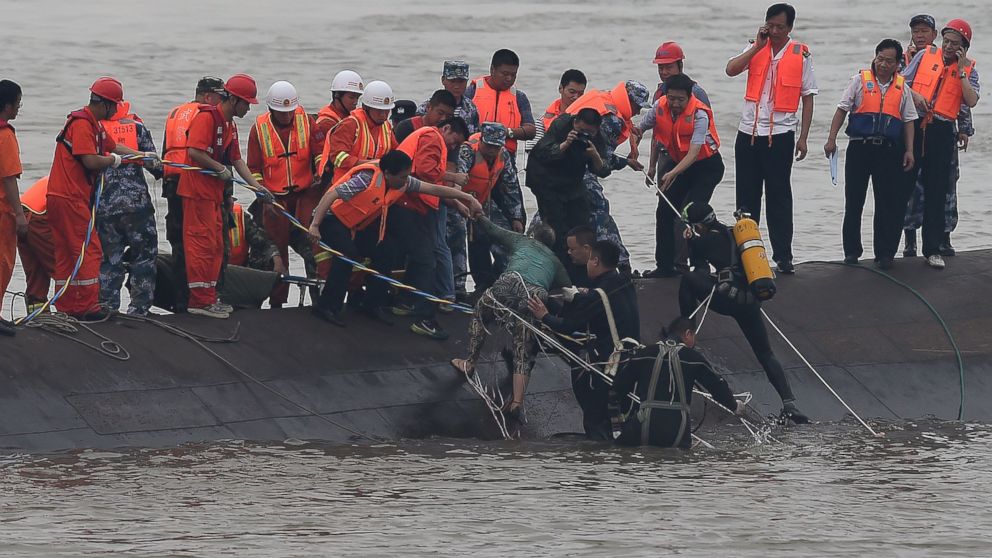 In this photo released by China's Xinhua News Agency, rescuers save a survivor, center, from the overturned passenger ship in the Jianli section of the Yangtze River in central China's Hubei Province Tuesday, June 2, 2015. Rescuers pulled several survivors to safety after hearing cries for help Tuesday from inside a capsized cruise ship that went down overnight in a storm on China's Yangtze River, state broadcaster CCTV said.