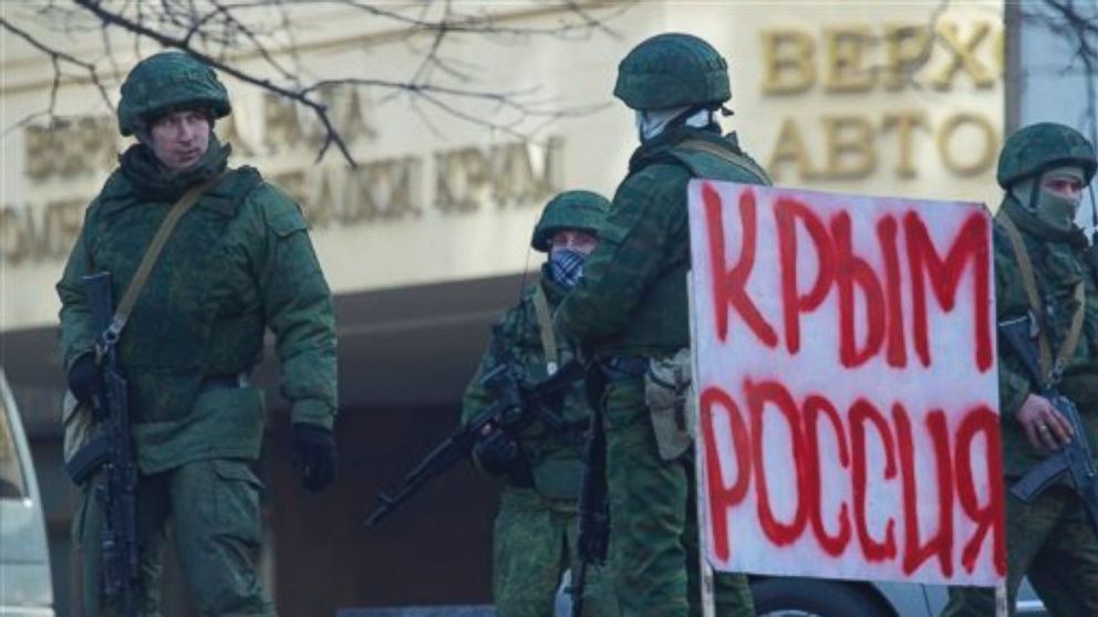 PHOTO: Unidentified gunmen wearing camouflage uniforms block the entrance of the Crimean Parliament building in Simferopol, Ukraine, Saturday, March 1, 2014. Poster reads "Crimea Russia".