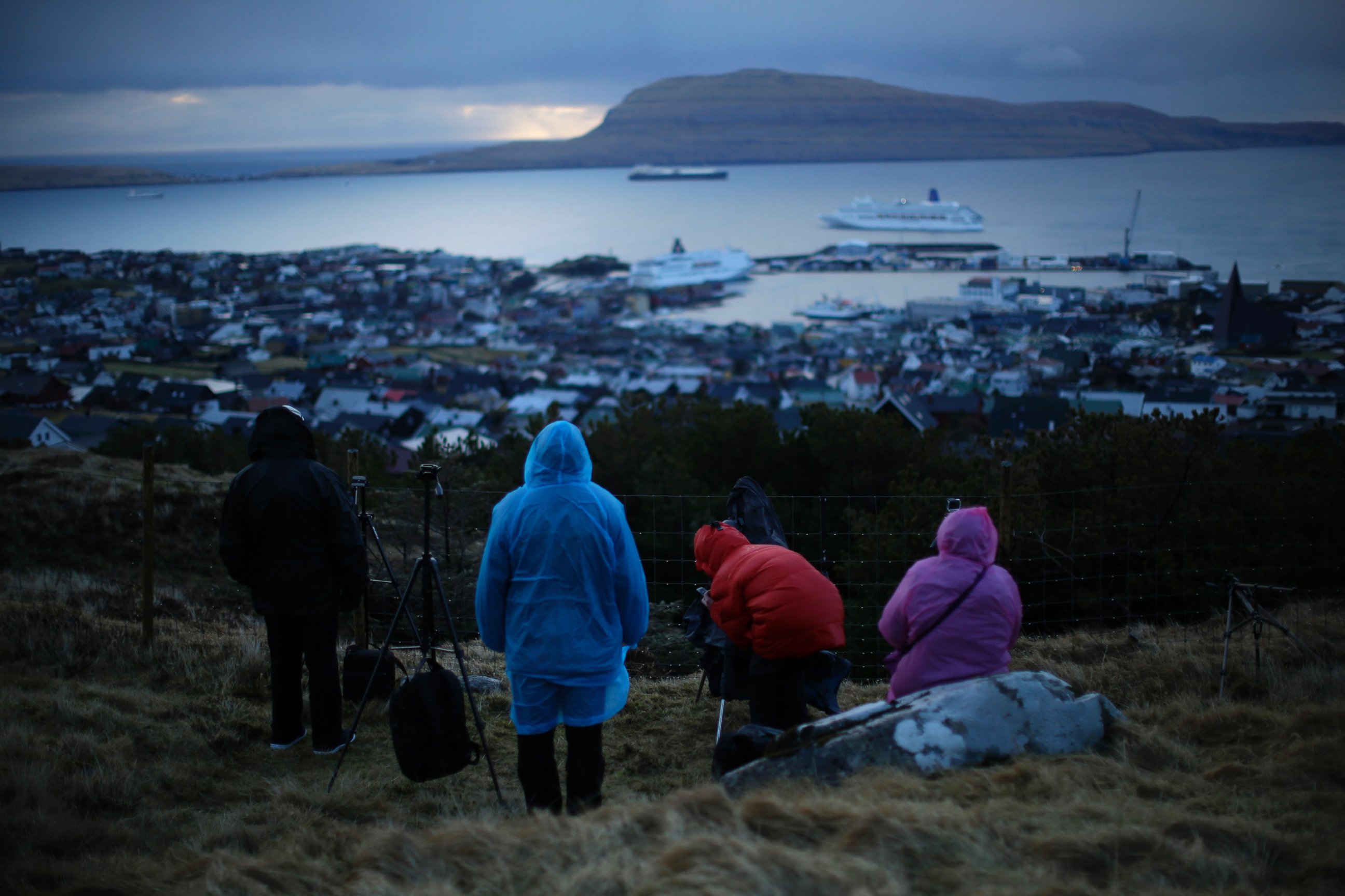 PHOTO: People wait for the start of a total solar eclipse on a hill beside a hotel overlooking the sea and Torshavn, the capital city of the Faeroe Islands, March 20, 2015.