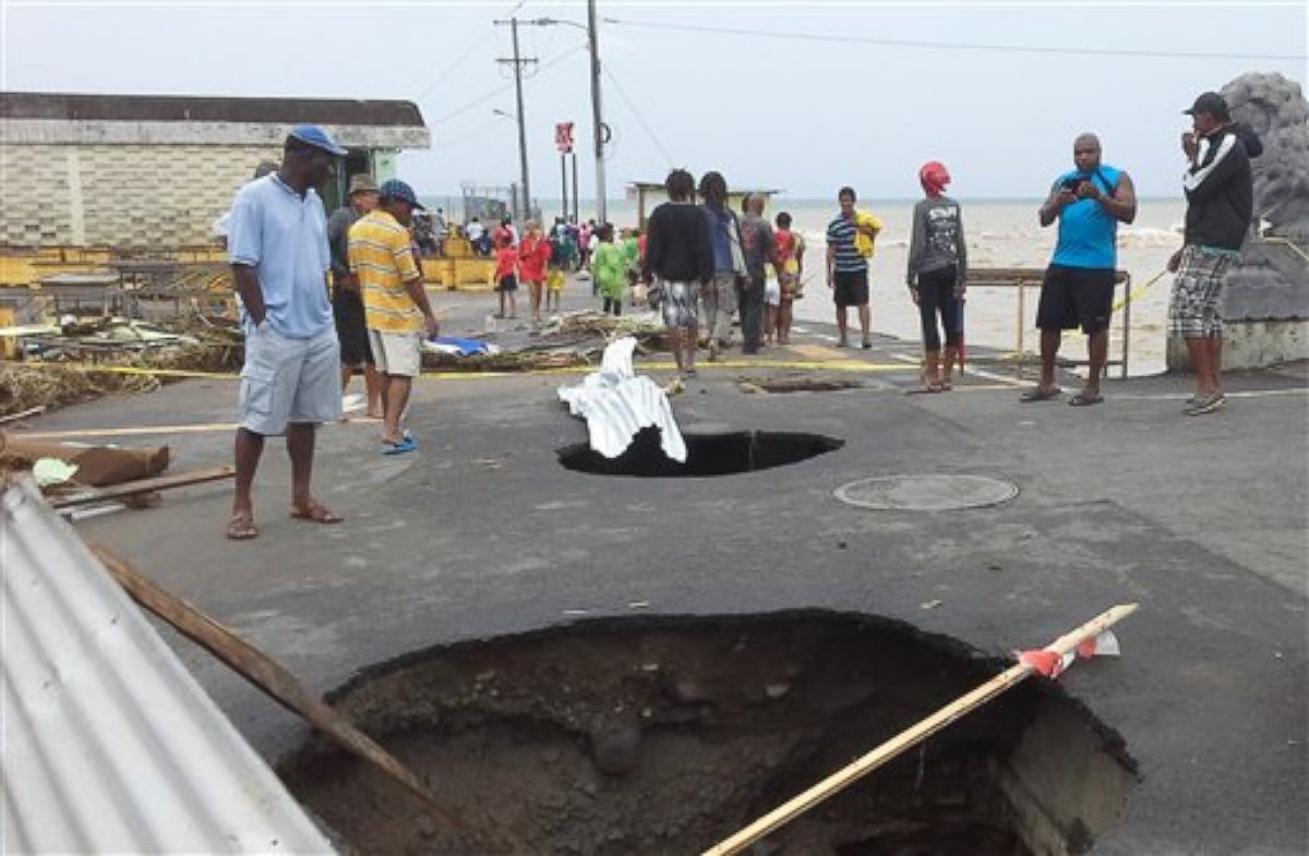 PHOTO: People look at sink holes in the road next to the capital's main market, Aug. 27, 2015, caused by Tropical Storm Erika in Roseau, Dominica. 