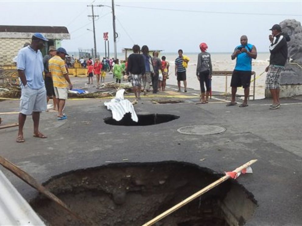 PHOTO: People look at sink holes in the road next to the capitals main market, Aug. 27, 2015, caused by Tropical Storm Erika in Roseau, Dominica.