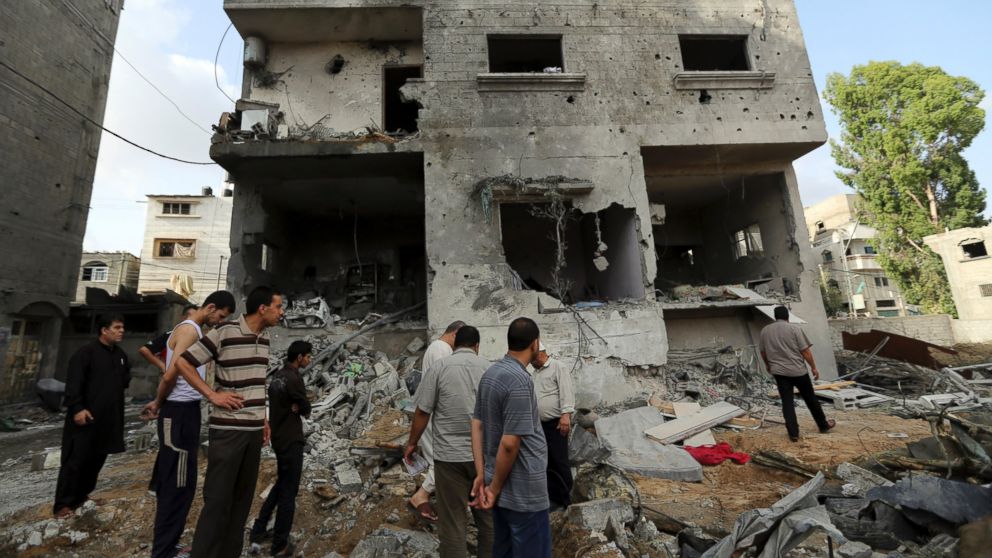 Palestinians gather outside the damaged house of Gaza's police chief Taysir al-Batsh after it was hit by an Israeli missile strike in Gaza City, Sunday, July 13, 2014. The strike that hit the home and damaged a nearby mosque as evening prayers ended Saturday, killed at least 18 people, wounded 50 and left some people believed to be trapped under the rubble, said Palestinian Health Ministry official Ashraf al-Kidra.
