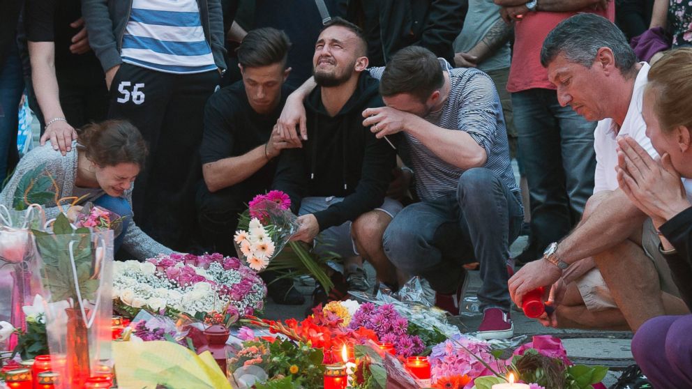 People mourn behind flower tributes near the Olympia shopping center where a shooting took place leaving nine people dead the day before, in Munich, July 23, 2016.