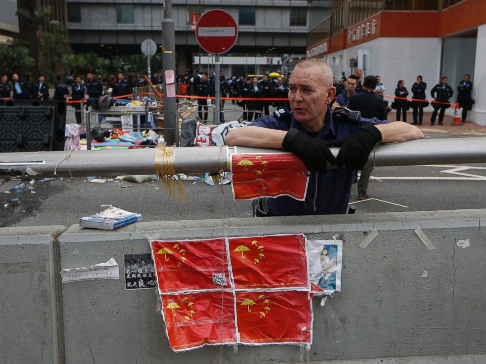 PHOTO: A police commander leans against a concrete wall with the defaced Chinese national flags placed on at the occupied area outside government headquarters in Hong Kong, Dec. 11, 2014.