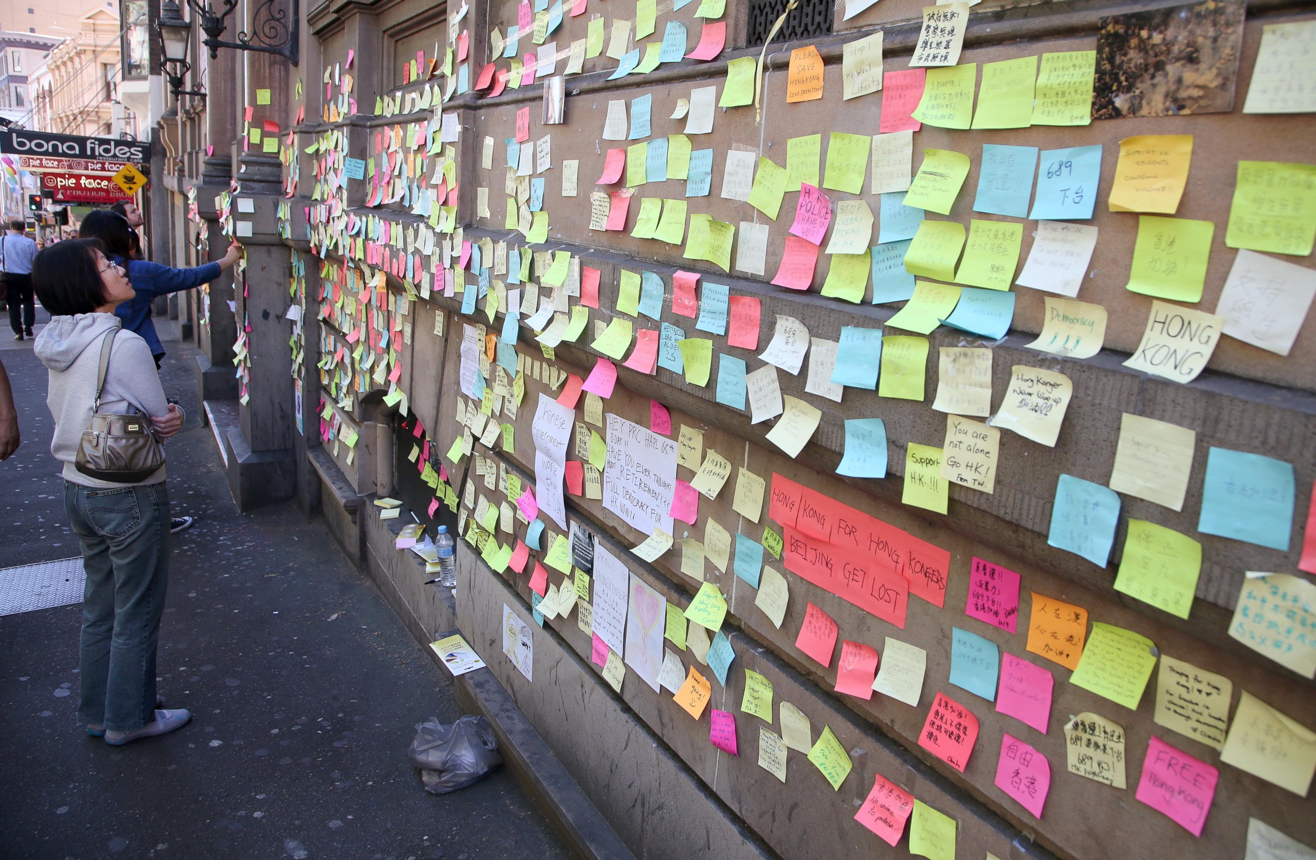 PHOTO: A woman looks at colorful post-it notes that are stuck on the outside of the Hong Kong building in Sydney, Oct. 1, 2014, to show support for the pro-democracy protesters in Hong Kong.