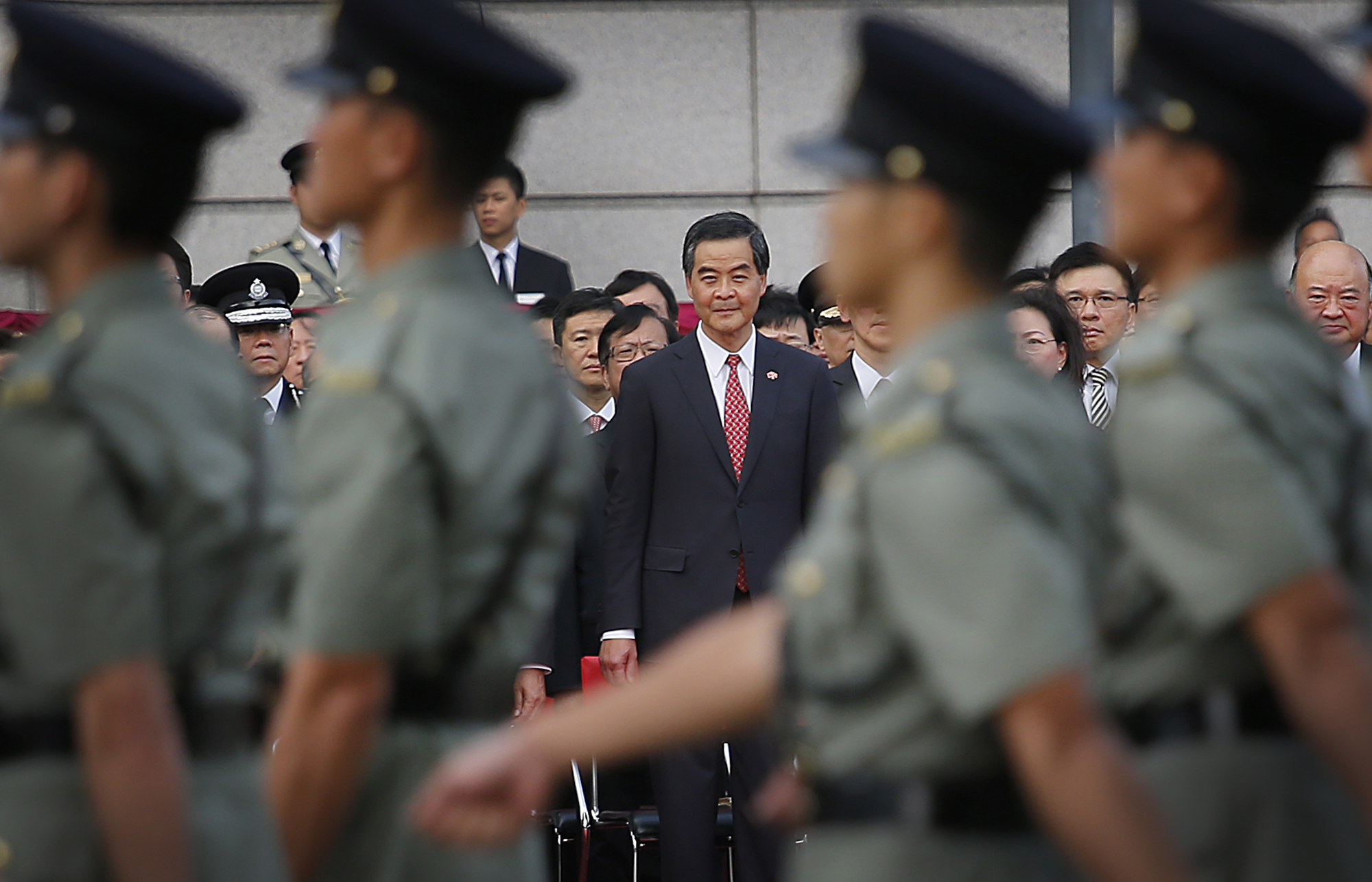 PHOTO: Hong Kong's Chief Executive Leung Chun-ying, center, watches as military personnel march during a flag-raising ceremony on Wednesday, Oct. 1, 2014 in Hong Kong.