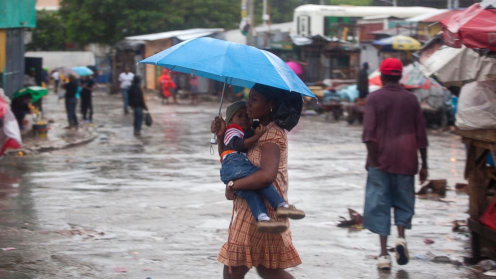 A woman carrying a child walks in the rain triggered by Hurricane Matthew in Port-au-Prince, Haiti, Oct. 4, 2016. Hurricane Matthew roared into the southwestern coast of Haiti on Tuesday, threatening a largely rural corner of the impoverished country with devastating storm conditions as it headed north toward Cuba and the eastern coast of Florida. 