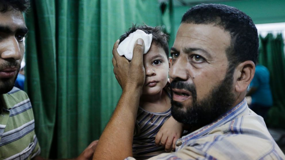 PHOTO: A Palestinian carries a boy, wounded in an Israeli strike at a house in Beit Lahiya, northern Gaza Strip, into the emergency room of the Kamal Adwan Hospital, in Beit Lahiya, Sunday, Aug. 3, 2014.