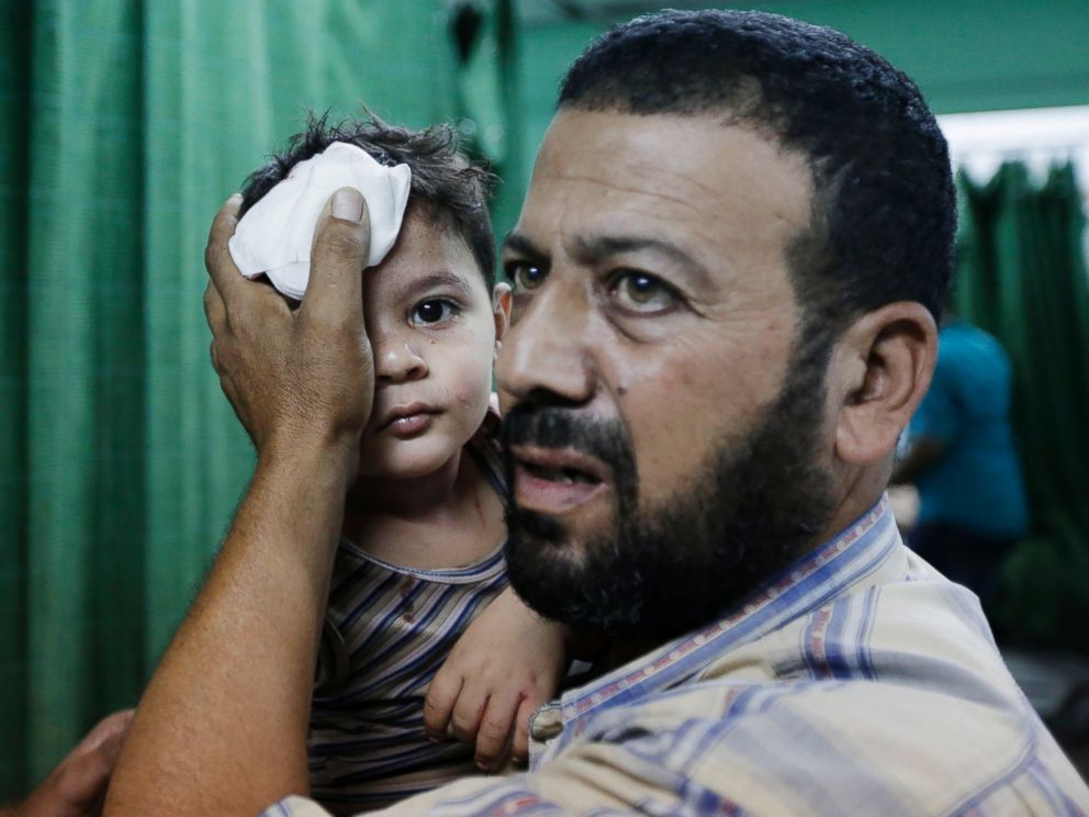 PHOTO: A Palestinian carries a boy, wounded in an Israeli strike at a house in Beit Lahiya, northern Gaza Strip, into the emergency room of the Kamal Adwan Hospital, in Beit Lahiya, Sunday, Aug. 3, 2014.