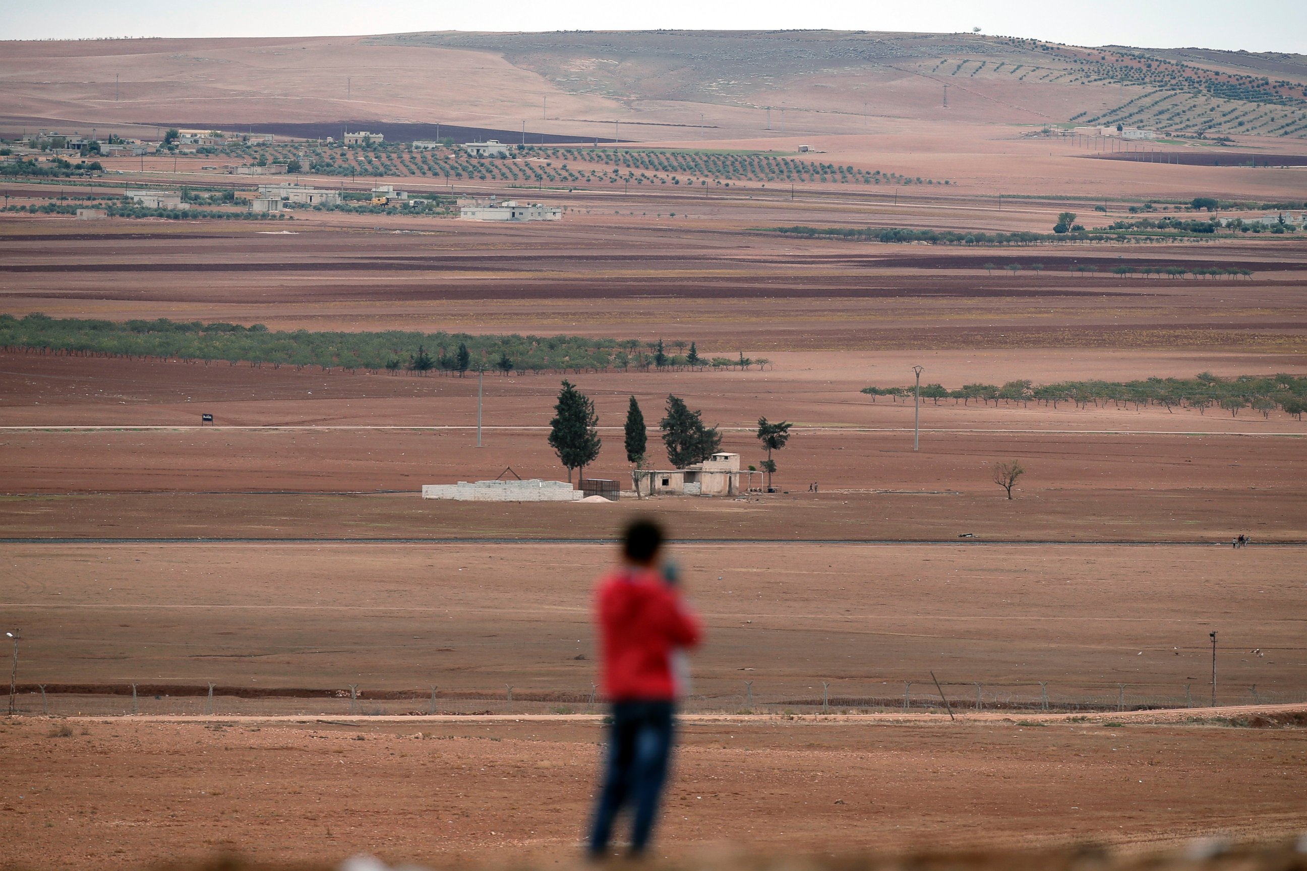 A boy uses a mobile phone to photograph the western outskirts of Kobani, Syria on the distance, as he stands on a hilltop on the outskirts of Suruc, at the Turkey-Syria border, Oct. 19, 2014.