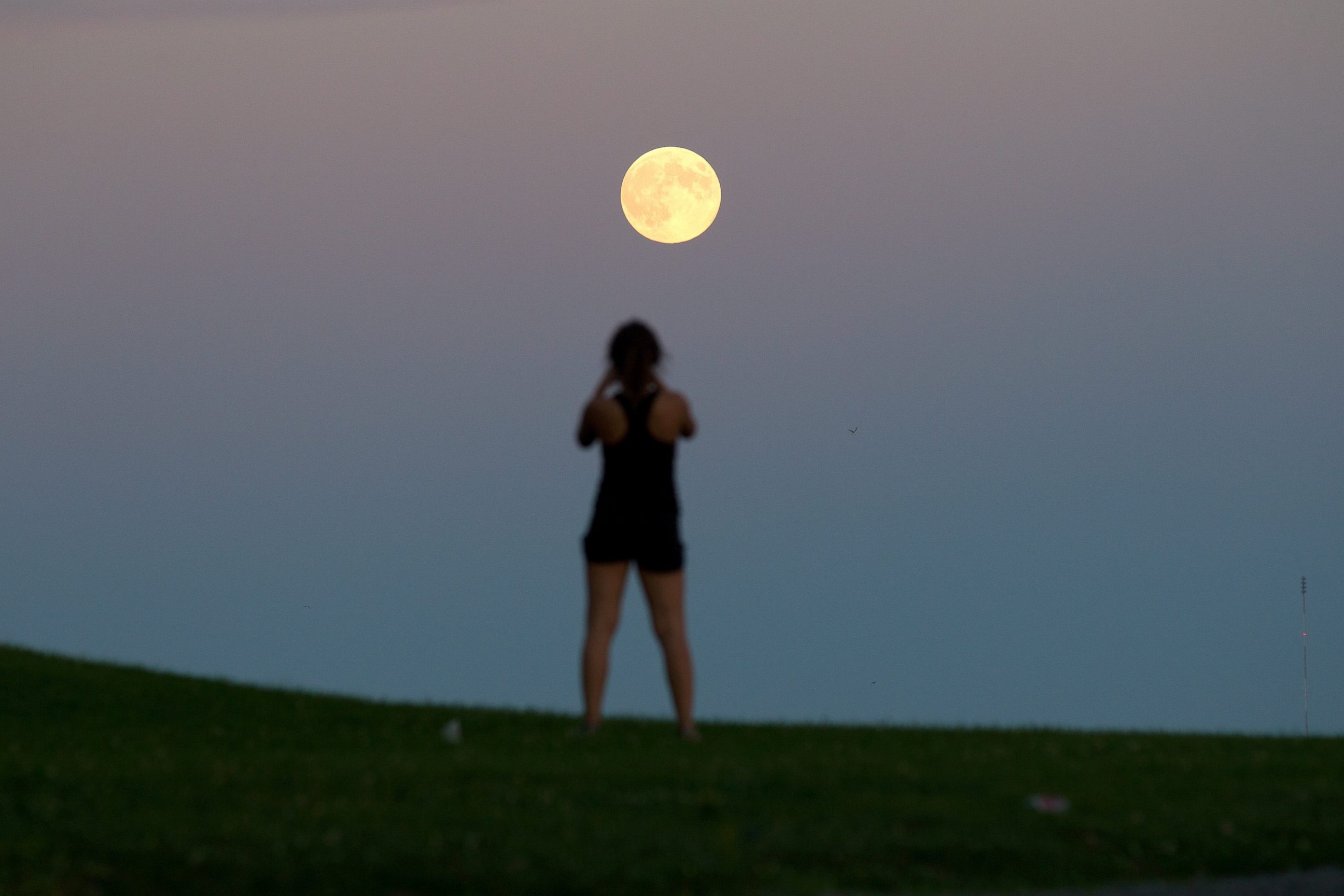 PHOTO: Queen's University student Lindsay Meier takes a picture of the moon as it rises over Lake Ontario in Kingston, Ontario, Sept. 8, 2014.