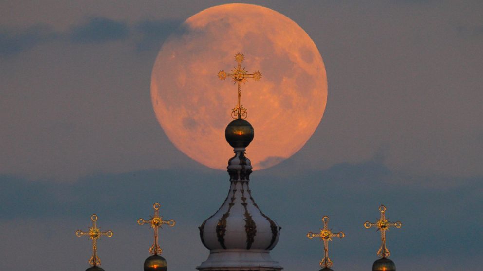 The full moon is seen rising in the sky above the domes of the Smolny Cathedral in St. Petersburg, Russia, Sept. 8, 2014.