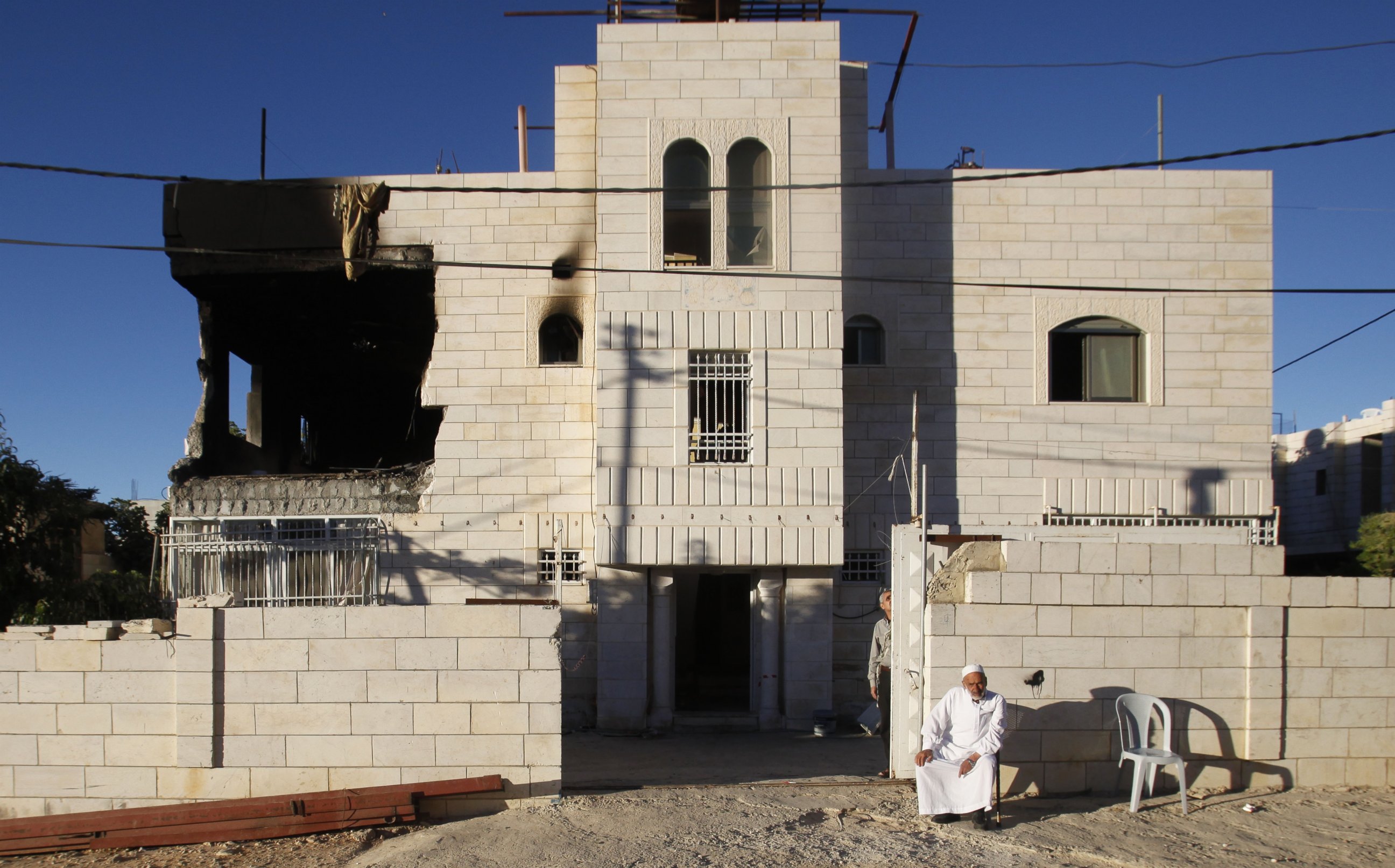 PHOTO: A Palestinian sits outside a home damaged by the Israeli army in the West Bank city of Hebron, July 1, 2014.