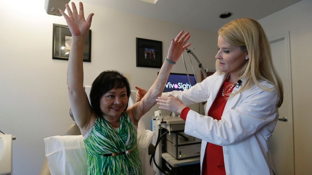 In this Sept. 26, 2015 photo, Dr. Jill Waibel examines Kim Phuc before the first of several laser treatments to reduce pain and the appearance of burn scars in her back and left arm in Miami from a napalm bomb in Vietnam 40 years ago. 