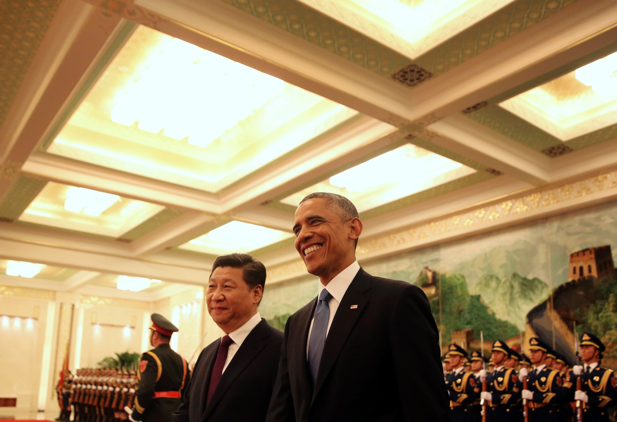 U.S. President Barack Obama, right, smiles after a group of children waved flags and flowers to cheer him during a welcome ceremony with Chinese President Xi Jinping at the Great Hall of the People in Beijing, Nov. 12, 2014.