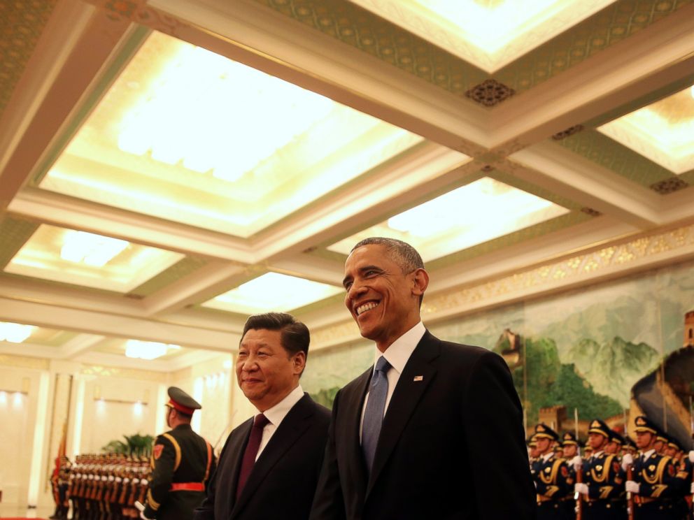 U.S. President Barack Obama, right, smiles after a group of children waved flags and flowers to cheer him during a welcome ceremony with Chinese President Xi Jinping at the Great Hall of the People in Beijing, Nov. 12, 2014.