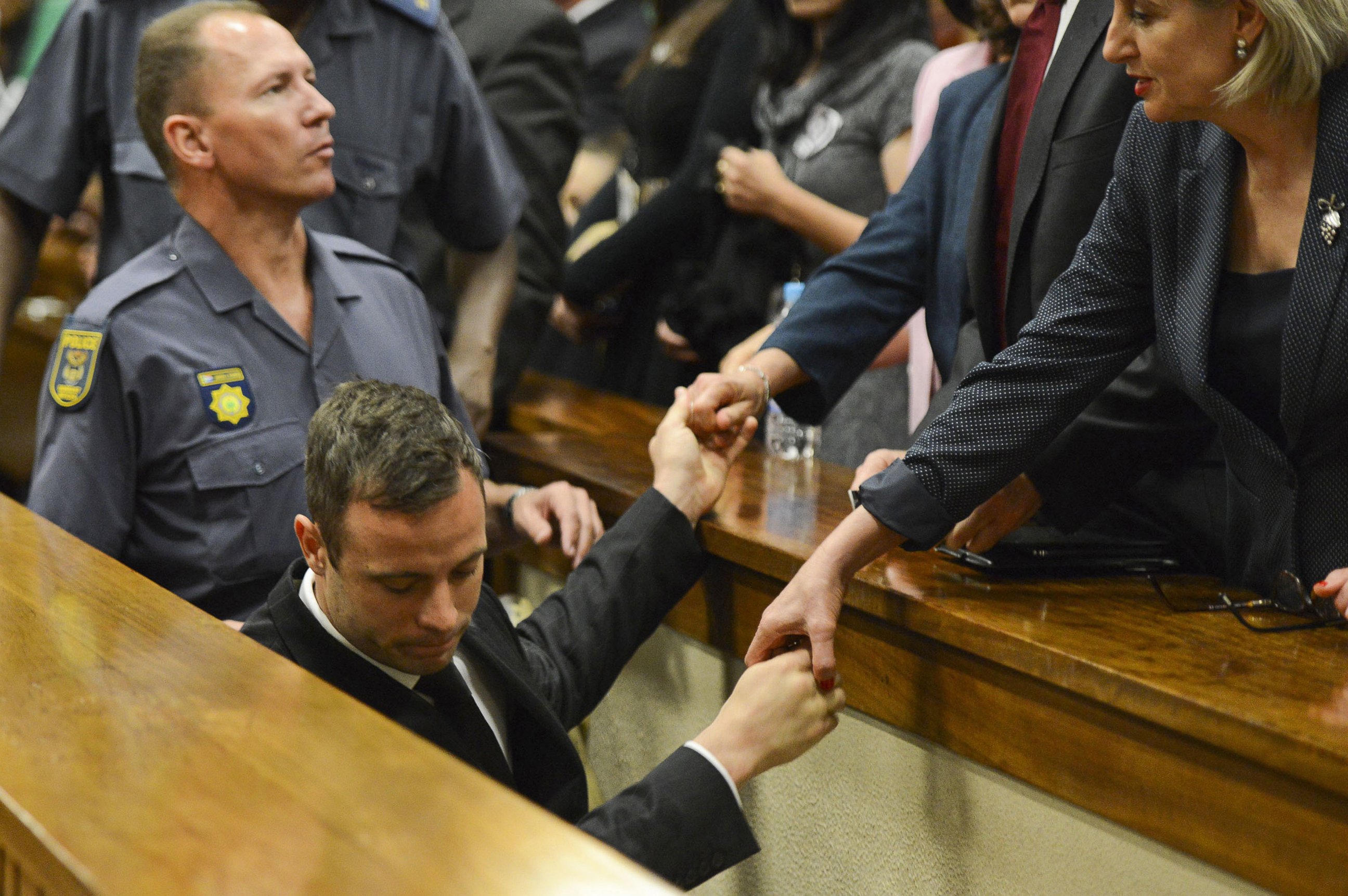 PHOTO: Oscar Pistorius, center,  touches hands with family members as he is led down to the cells of the court in Pretoria, South Africa, Oct. 21, 2014.