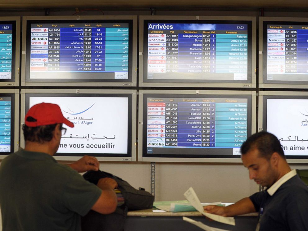 PHOTO: People stand next to an arrival information screen showing the delayed Air Algerie flight 5017 at the Houari Boumediene airport near Algiers, Algeria, July 24, 2014.