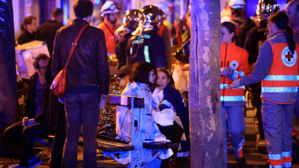 People rest on a bench after being evacuated from the Bataclan theater after a shooting in Paris, Friday Nov. 13, 2015. French President Francois Hollande declared a state of emergency and announced that he was closing the country's borders.