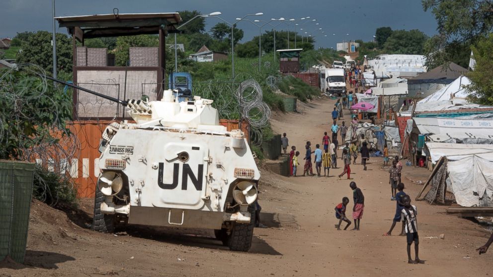 In this photo taken, July 25, 2016, some of the more than 30,000 Nuer civilians sheltering in a United Nations base in South Sudan's capital Juba for fear of targeted killings by government forces walk by an armored vehicle and a watchtower manned by Chinese peacekeepers. 