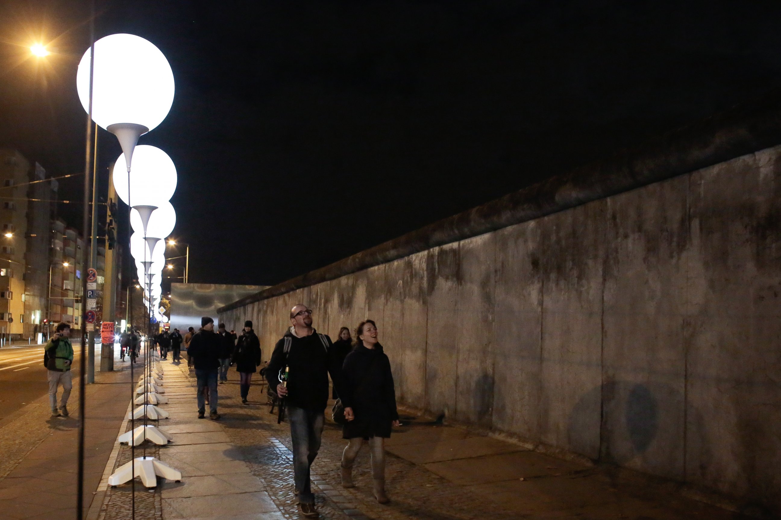 PHOTO: People walk between balloons of the art project 'Lichtgrenze 2014' (lit. 'lightborder 2014') and the remains of the former Berlin Wall at the wall memorial site Bernauer Strasse in Berlin, Germany, Nov. 7, 2014. 