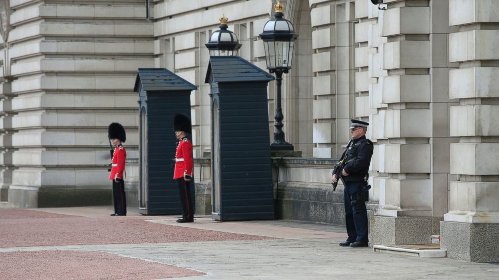 An armed police officer and soldiers from the Irish Guards are seen on guard after a security breach at Buckingham Palace in central London, May 19, 2016.  