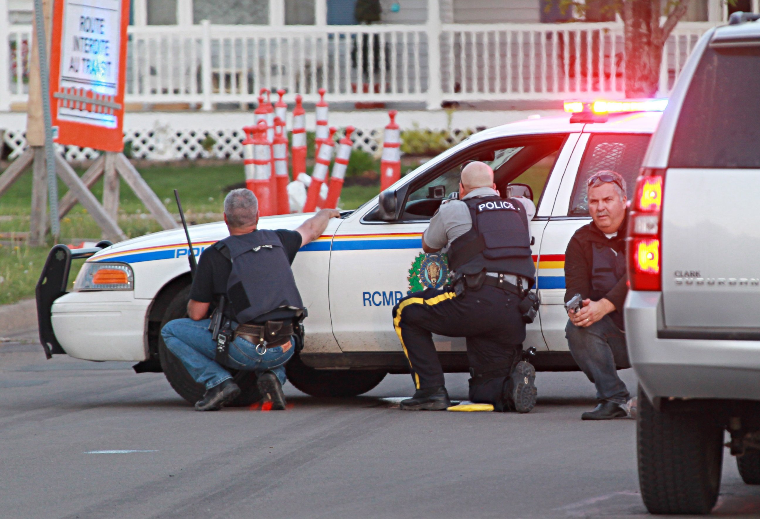 PHOTO: Police officers take cover behind their vehicles in Moncton, New Brunswick, June 4, 2014 following a shooting.