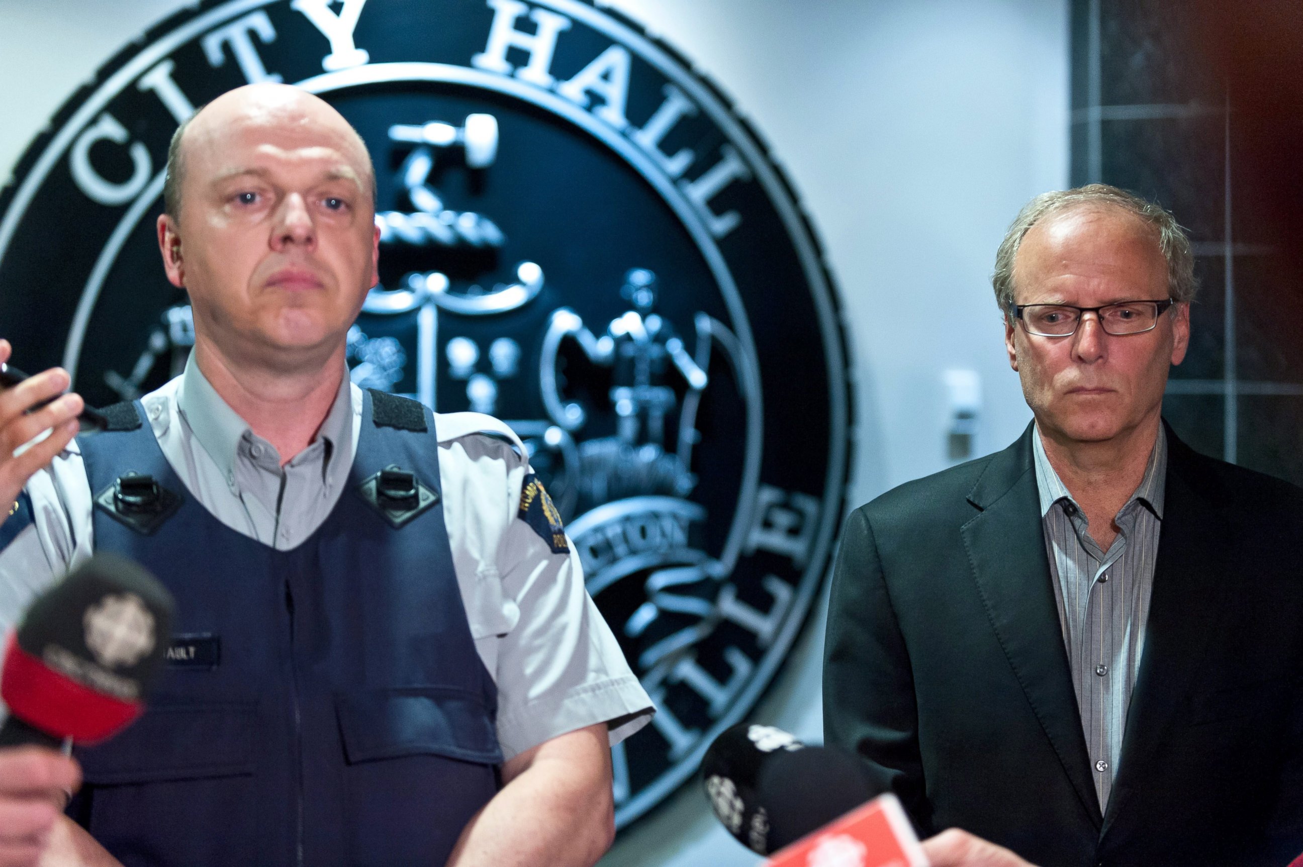 PHOTO: Royal Canadian Mounted Police officer Damien Theriault and Mayor George LeBlanc pause to collect themselves before addressing the media during a late night news conference at City Hall in Moncton,  New Brunswick, June 4, 2014.
