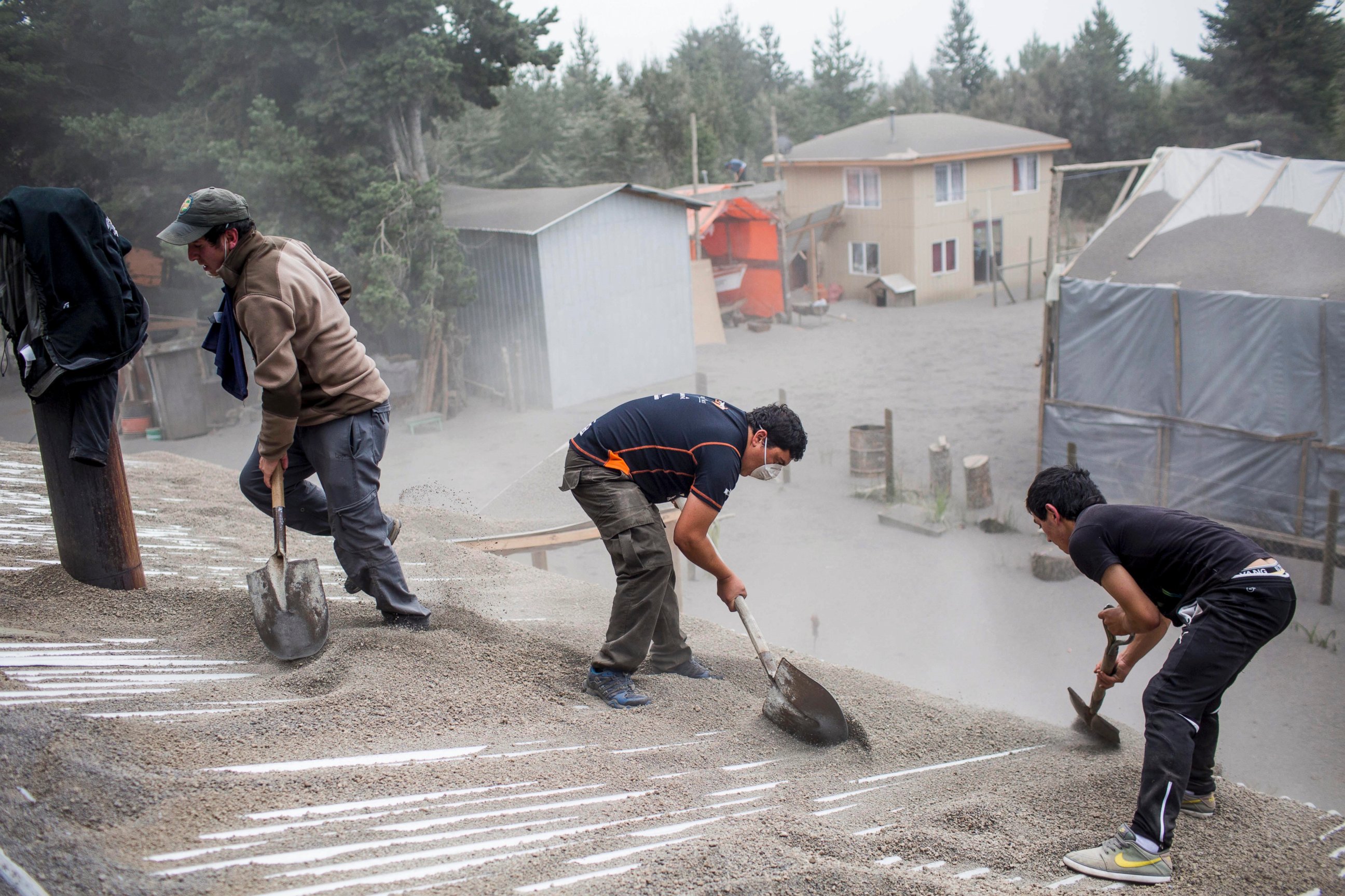 PHOTO: Men remove ash from a building's roof, left by the Calbuco volcano, in Ensenada, Chile, April 23, 2015. 