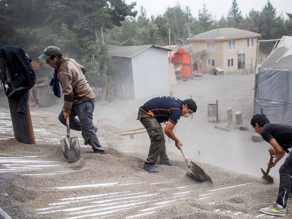 PHOTO: Men remove ash from a buildings roof, left by the Calbuco volcano, in Ensenada, Chile, April 23, 2015.